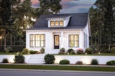 a small white house with black roof and two windows on the front, surrounded by trees