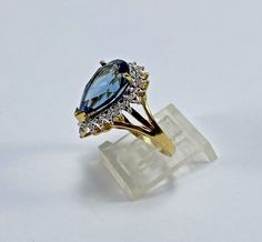 a blue and white diamond ring sitting on top of a clear stand