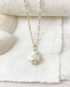 This elegant Baroque Pearl and Aquamarine Necklace is a luxurious statement piece featuring a large baroque pearl suspended on a chain of shimmering micro-faceted pale blue aquamarine gemstone beads, all handcrafted with beautiful gold fill. This coastal-inspired necklace is perfect for adding an elegant touch to any look, either solo or layered with other pieces. Necklace length: 16 inches plus 2 inch extender Materials: baroque pearl, aquamarine gemstone beads, gold filled clasp, wire and comp Unique Mother Of Pearl Jewelry With Pearl Pendant, Unique White Baroque Pearl Jewelry, Bohemian Baroque Pearl Jewelry As Gift, Bohemian Baroque Pearl Jewelry For Gift, Bohemian Baroque Pearl Jewelry Gift, Elegant Baroque Pearl Shell Necklace As Gift, Unique Pearl Drop Necklace For Wedding, Unique Handmade Baroque Pearl Necklace, Handmade Unique Baroque Pearl Necklace