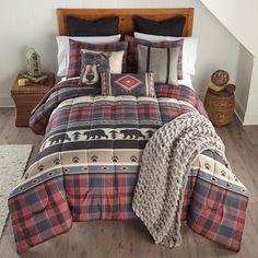 a bed in a bedroom with plaid comforter and pillows