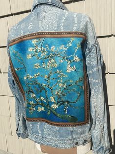 a blue jacket with an almond blossoming tree painted on it's chest and back