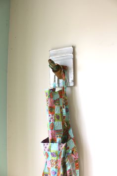 a bird perched on top of a piece of fabric hanging from a hook in a wall