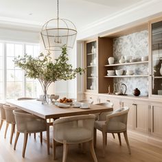 a dining room table with chairs and vases on the shelves in front of it