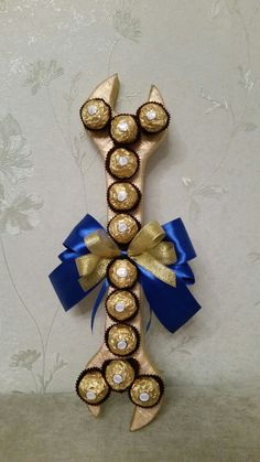 a gold and blue bow with chocolates in it's center on a wall