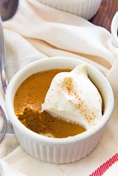 a white bowl filled with food on top of a table next to two spoons