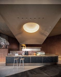 an open kitchen with two stools in front of the counter and ceiling lights above it