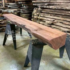 a bench made out of wood and metal legs in a warehouse with stacks of lumber