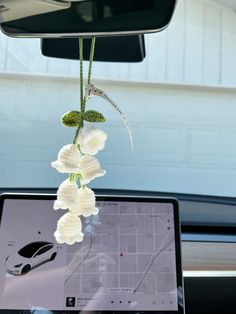 a laptop computer sitting on top of a desk in front of a car window with flowers hanging from it