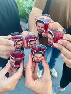 several people holding up wine glasses with pictures on the cups in front of their faces