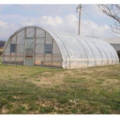 a green house sitting on top of a lush green field