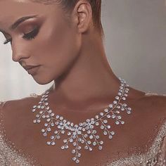 a woman wearing a silver necklace with crystal stones on it's neck and shoulder