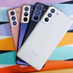 three samsung phones are sitting next to each other on a colorful surface with an abstract design in the background