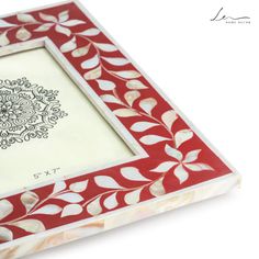 a red and white photo frame with an intricate design on the front, sitting against a white background