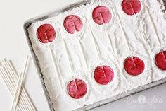 a cake with white frosting and red circles on it next to two toothpicks