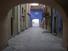 an arch in the middle of a cobblestone street with buildings on either side