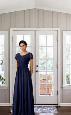 a woman standing in front of a door wearing a dress