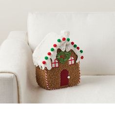 a small gingerbread house sitting on top of a white couch next to a pillow