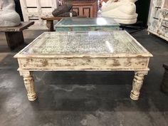 an old coffee table with glass top in a shop