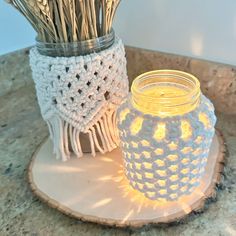 two crocheted mason jars sitting on top of a wooden stand next to each other