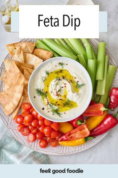 a white plate topped with dip surrounded by veggies and crackers