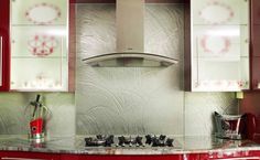 a kitchen with red cabinets and white counter tops, including a stove top oven hood