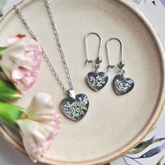 two heart shaped pendants on a plate next to flowers