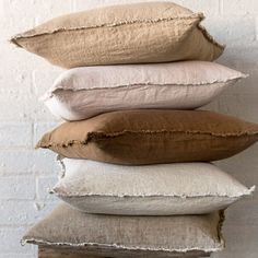 four pillows stacked on top of each other in front of a brick wall with white bricks