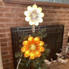 a flower shaped light hanging from the ceiling in front of a fire place with a christmas tree behind it