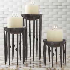 four candles sitting on top of each other in front of a white brick wall and floor