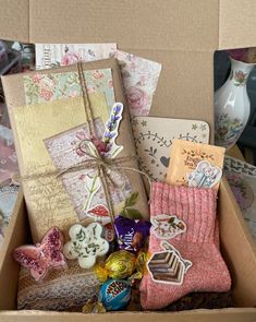 a box filled with lots of assorted items on top of a table next to a vase