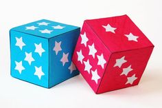 two wooden dices with white stars on them, one pink and one blue are facing each other