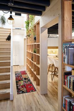 a room with wooden floors and stairs leading to the upper floor, along with bookshelves that have plants on them