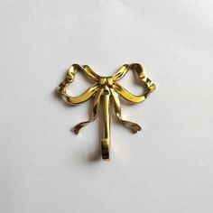 a gold bow brooch sitting on top of a white surface