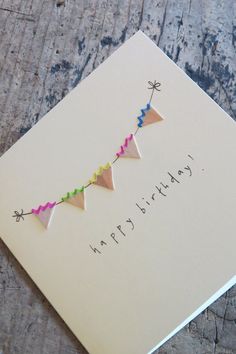 a happy birthday card with an arrow and streamers on the front, sitting on top of a piece of wood