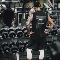 a man standing in front of a row of dumbbells with his back turned to the camera