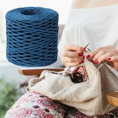 a woman is knitting on a chair with a blue yarn ball in front of her