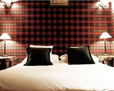 a bed with two lamps on either side of it and a plaid wall behind it