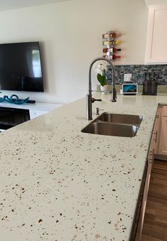 a kitchen counter with a sink and a television in the backgroung area