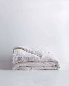 two white linens stacked on top of each other in front of a white wall