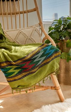 a chair with a green blanket on top of it next to a potted plant