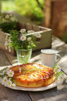 a small pastry on a plate with flowers and a glass of milk next to it