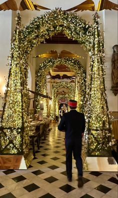 a man in a suit is walking down the hall decorated with lights and garlands