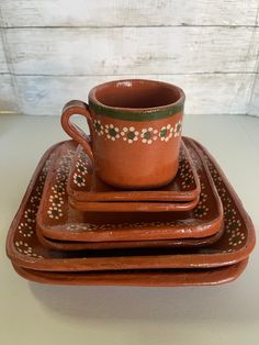 a set of four brown and green ceramic dishes with flower designs on the rims