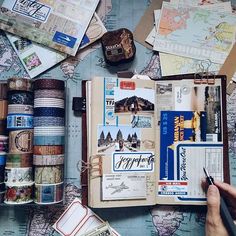 a person holding a pen and looking at an open book with many different things on it