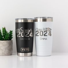 two yeti tumblers next to a potted plant on a table with the words class of 202 printed on them