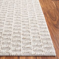 a white rug on top of a wooden floor next to a hard wood flooring