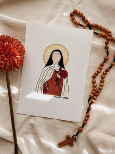 a card with an image of the virgin mary holding a red rose on a white sheet