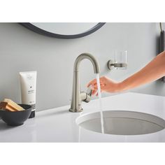 a person is washing their hands under the faucet in front of a sink