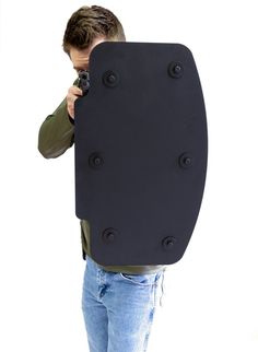 a man holding a camera up to his face with a large black object on it's back