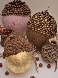 several decorative vases are arranged on a table with flowers and leaves in them, including pine cones